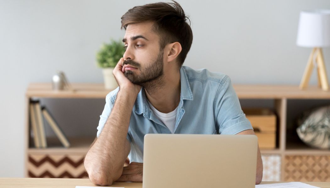 Man staring away from his laptop feeling distracted during work.