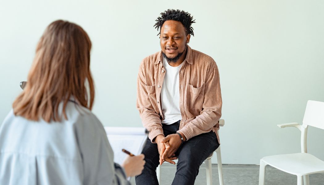 Man sitting across from a therapist smiling while engaged in a conversation.
