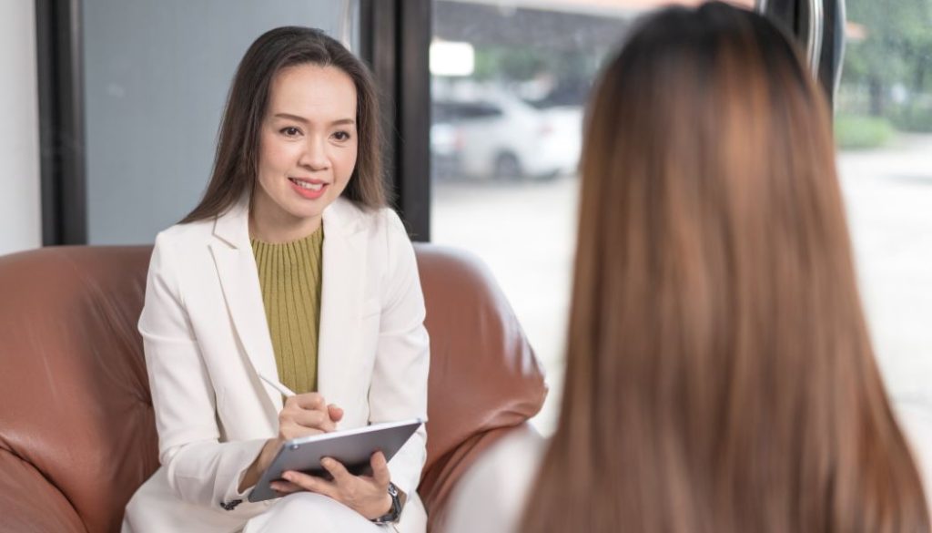 Therapist smiling and taking notes while talking to a patient.