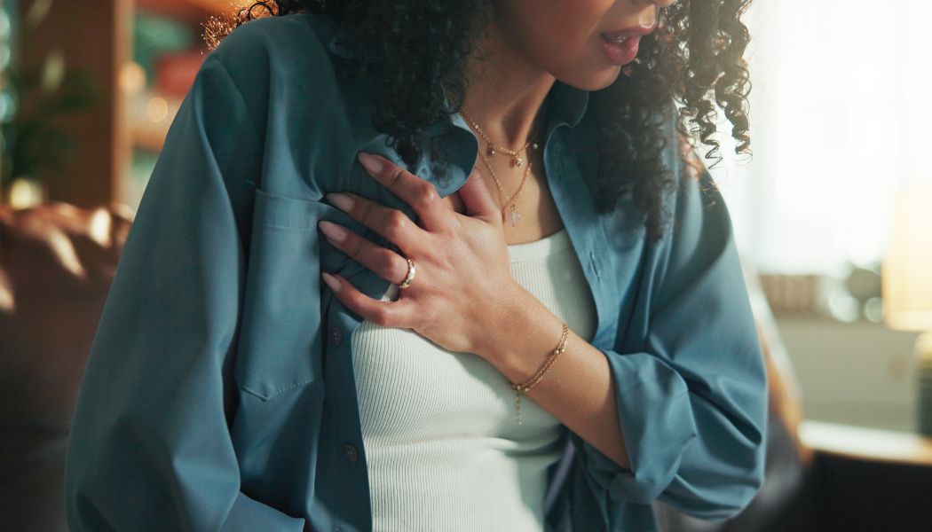 Woman having an anxiety attack while clutching her chest with one hand.