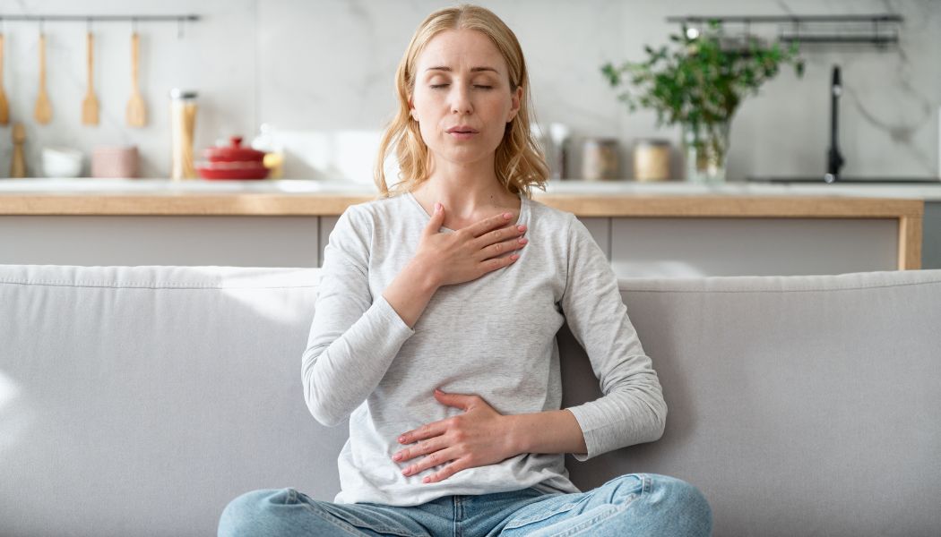 Woman practicing deep breathing with her hand on her chest and abdomen.